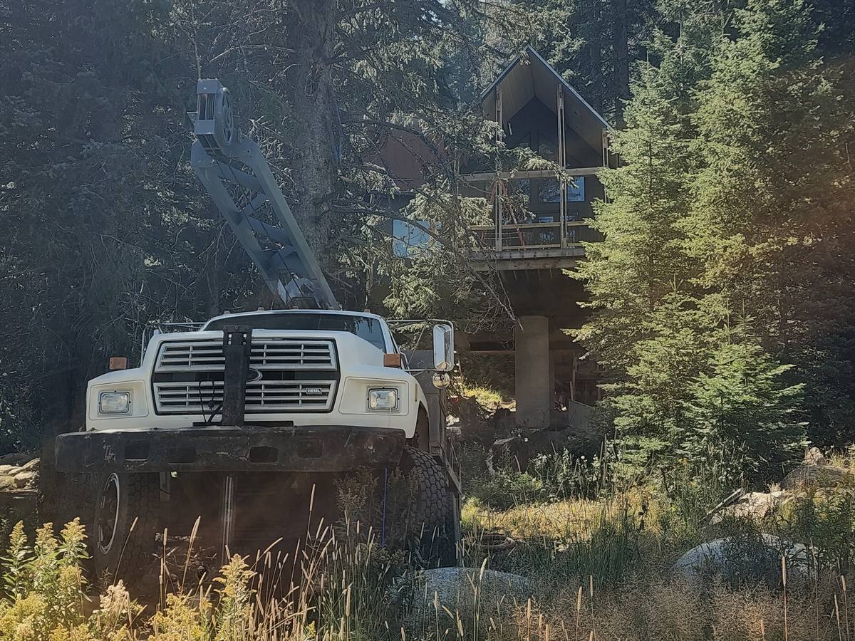 Aqua Terra drill rig set up at a wooded mountain property below an elevated cabin