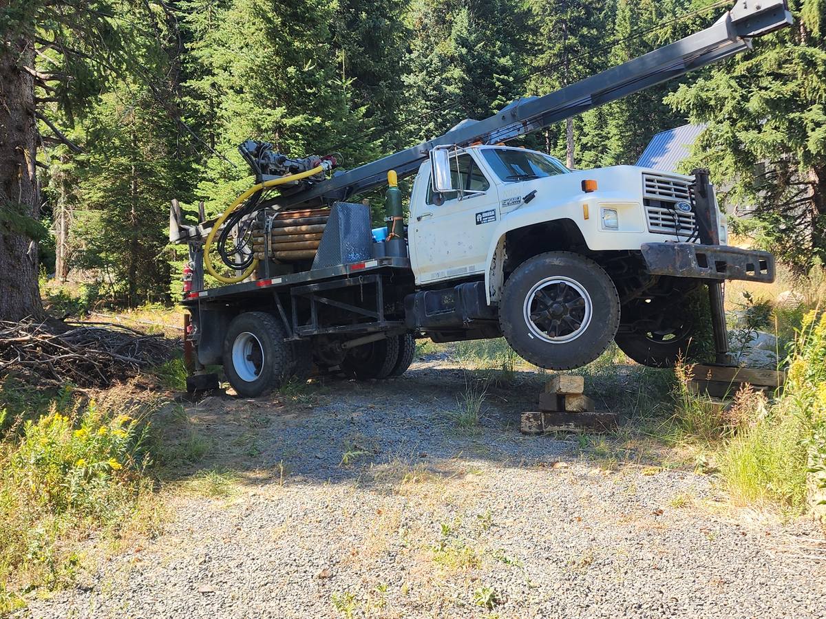 Aqua Terra drill truck jacked and cribbed level on a sloped gravel pad before drilling